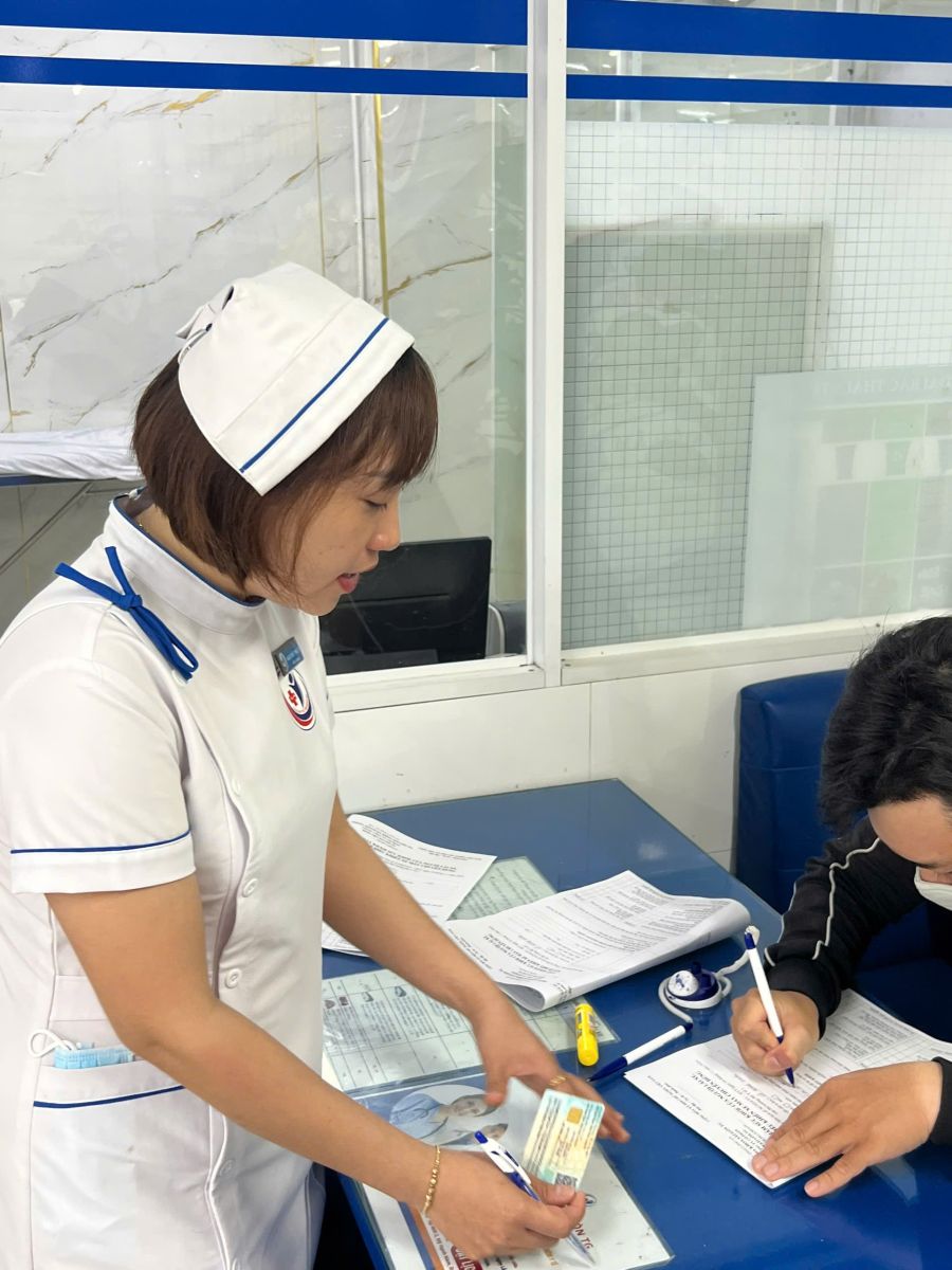 Nhân viên y tế tiếp đón và hướng dẫn tận tình cho bệnh nhân khám BHYT tại quầy đăng ký